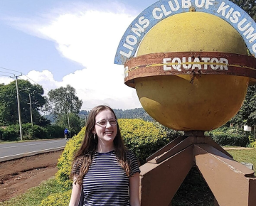 Student studying abroad stands at the Equator