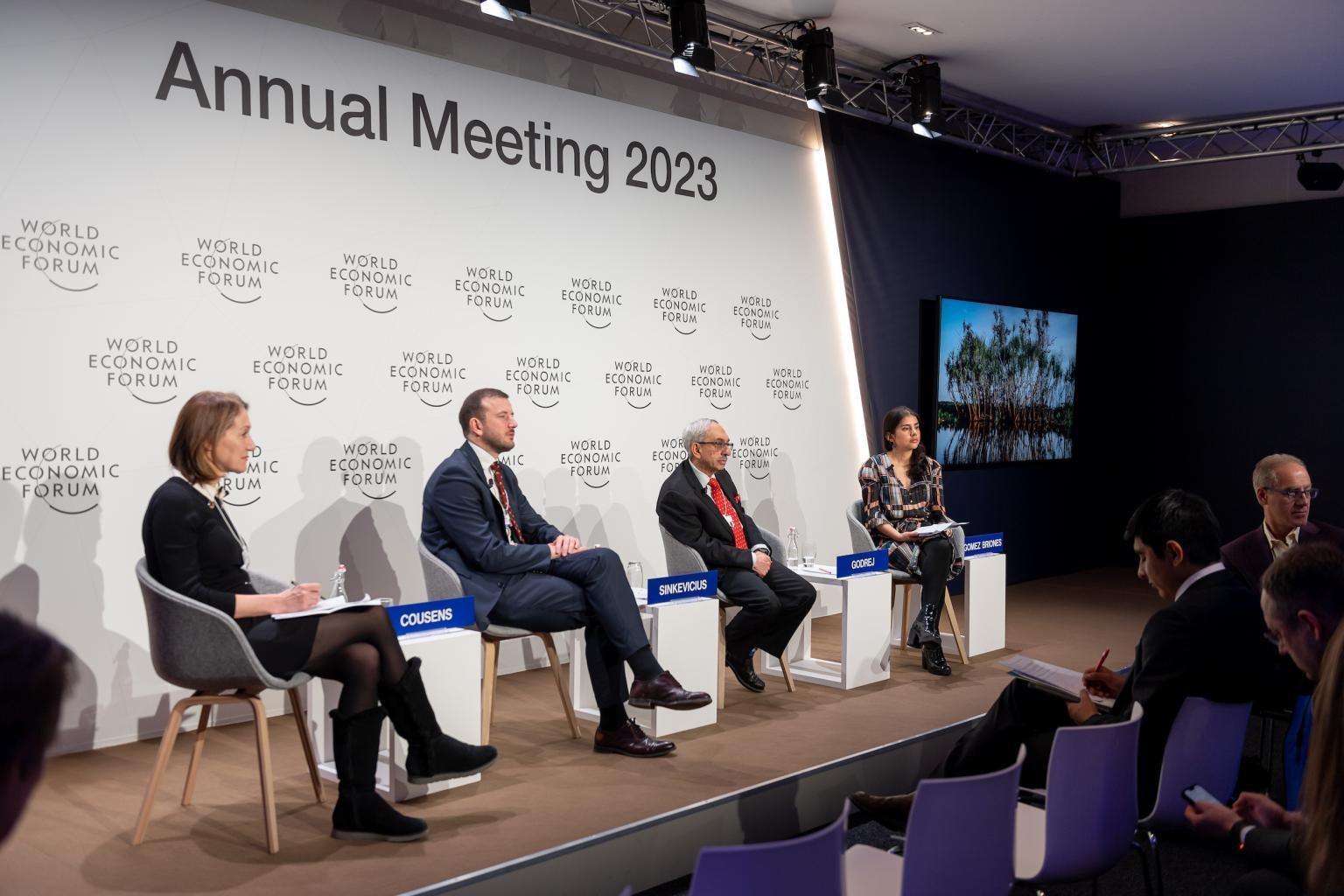 "Panel of four people on stage against a step-repeat backdrop with the World Economic Forum logo"