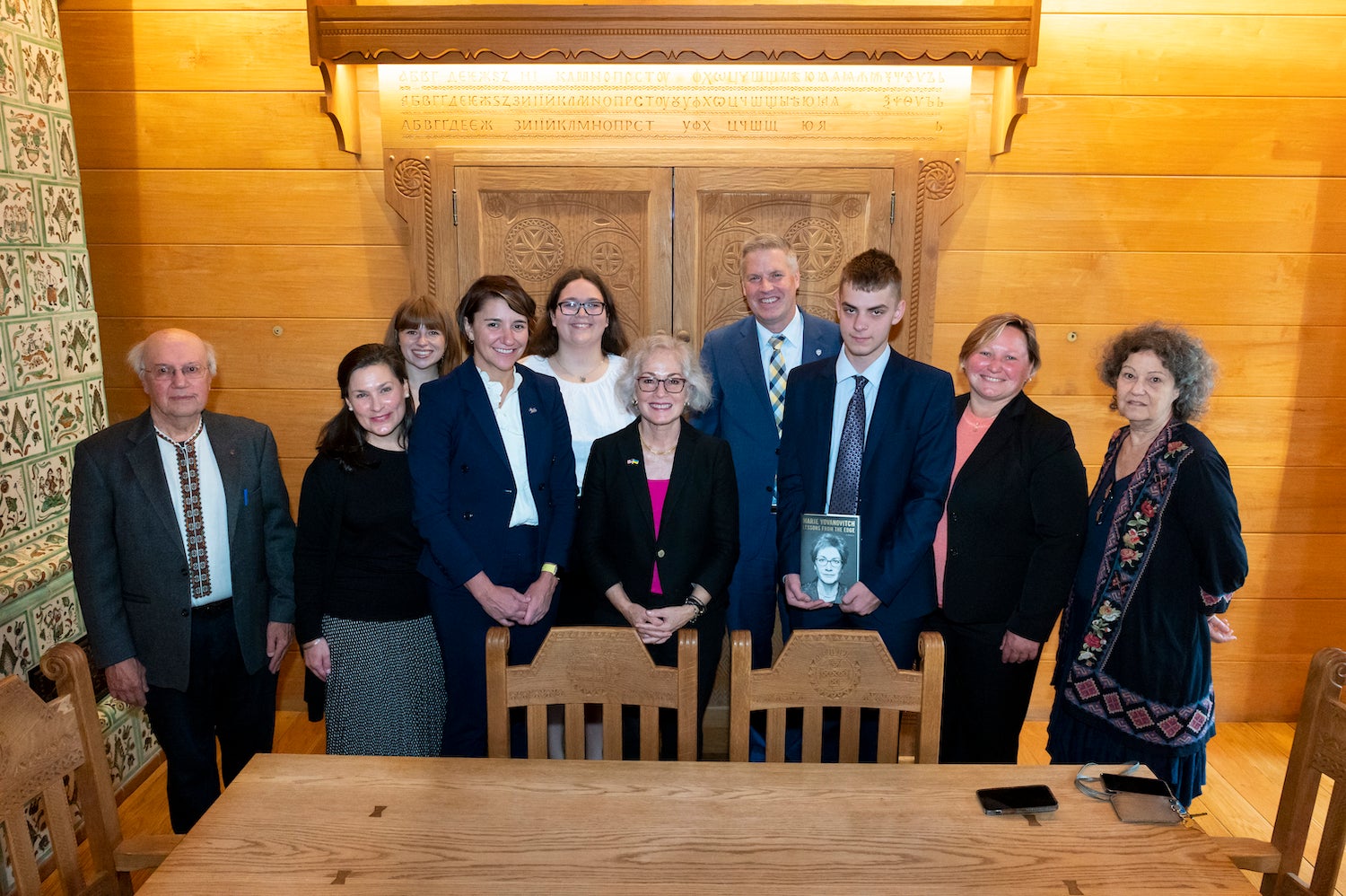 "Marie Yovanovitch, Dean Carissa Slotterback, Chancellor Patrick Gallagher, and 7 other Pitt community members pose for a group photo in the Ukrainian Nationality Room. One student holds a copy of Yovanovitch's memoir, Lessons from the Edge."