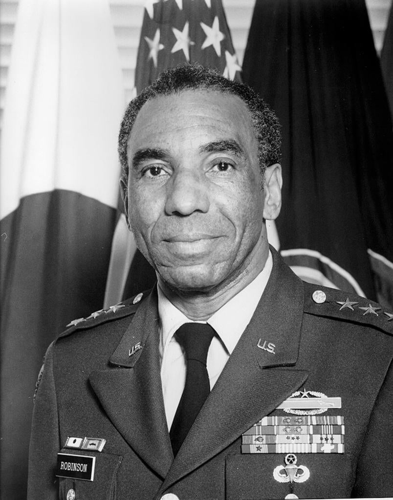 "Black and white headshot of General Roscoe Robinson Jr in army uniform, with the US and Japan flags behind him"