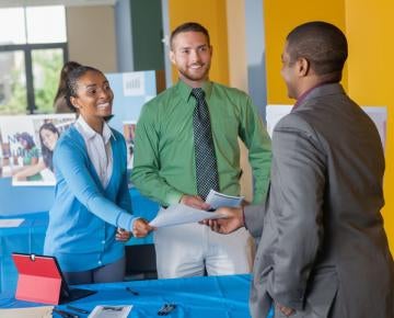 Young professional accepting business card from team at job fair