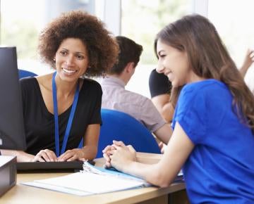 Two women huddled around computer