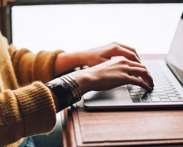 student typing on laptop computer