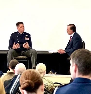 Prof Michael Kenney moderates Q&A with General Thompson on stage; backs of audience heads