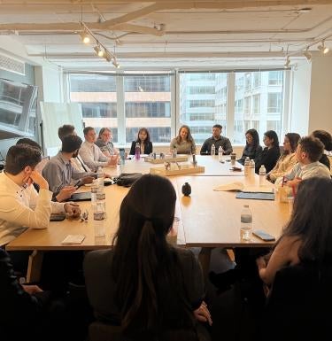 Students are seated around a conference table with a GSPIA alumni working in DC.