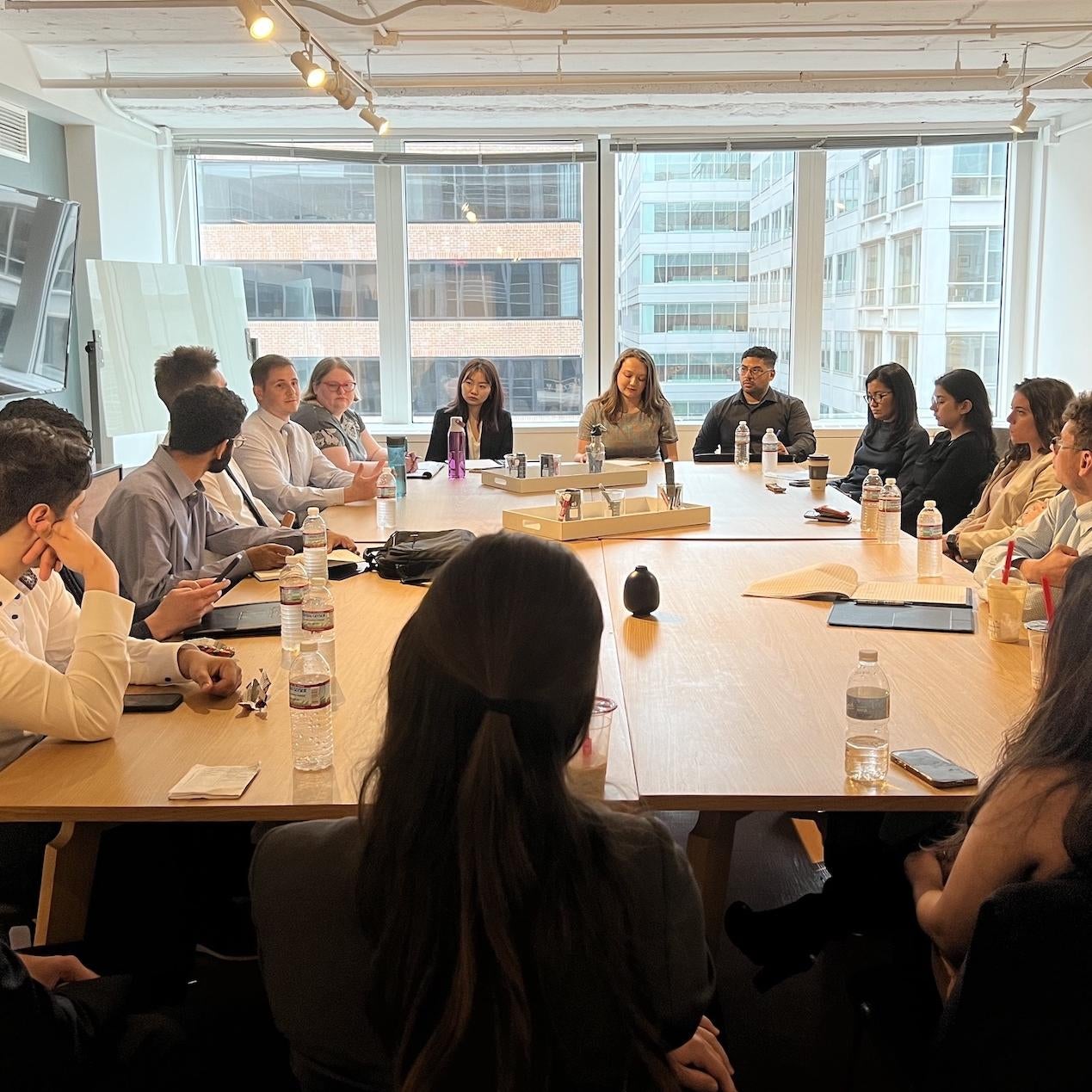 Students are seated around a conference table with a GSPIA alumni working in DC.